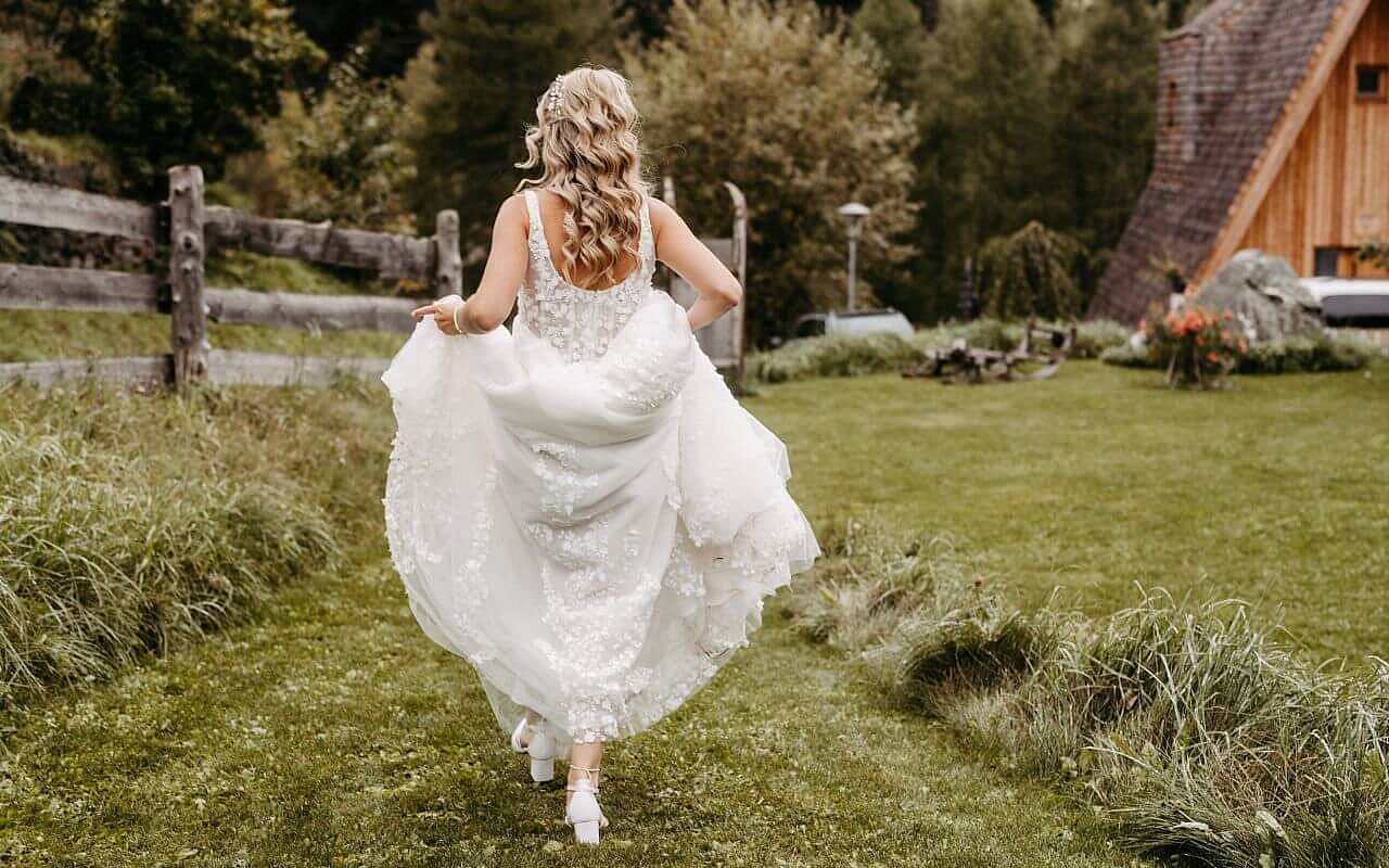 Braut läuft in Brautkleid über Gras